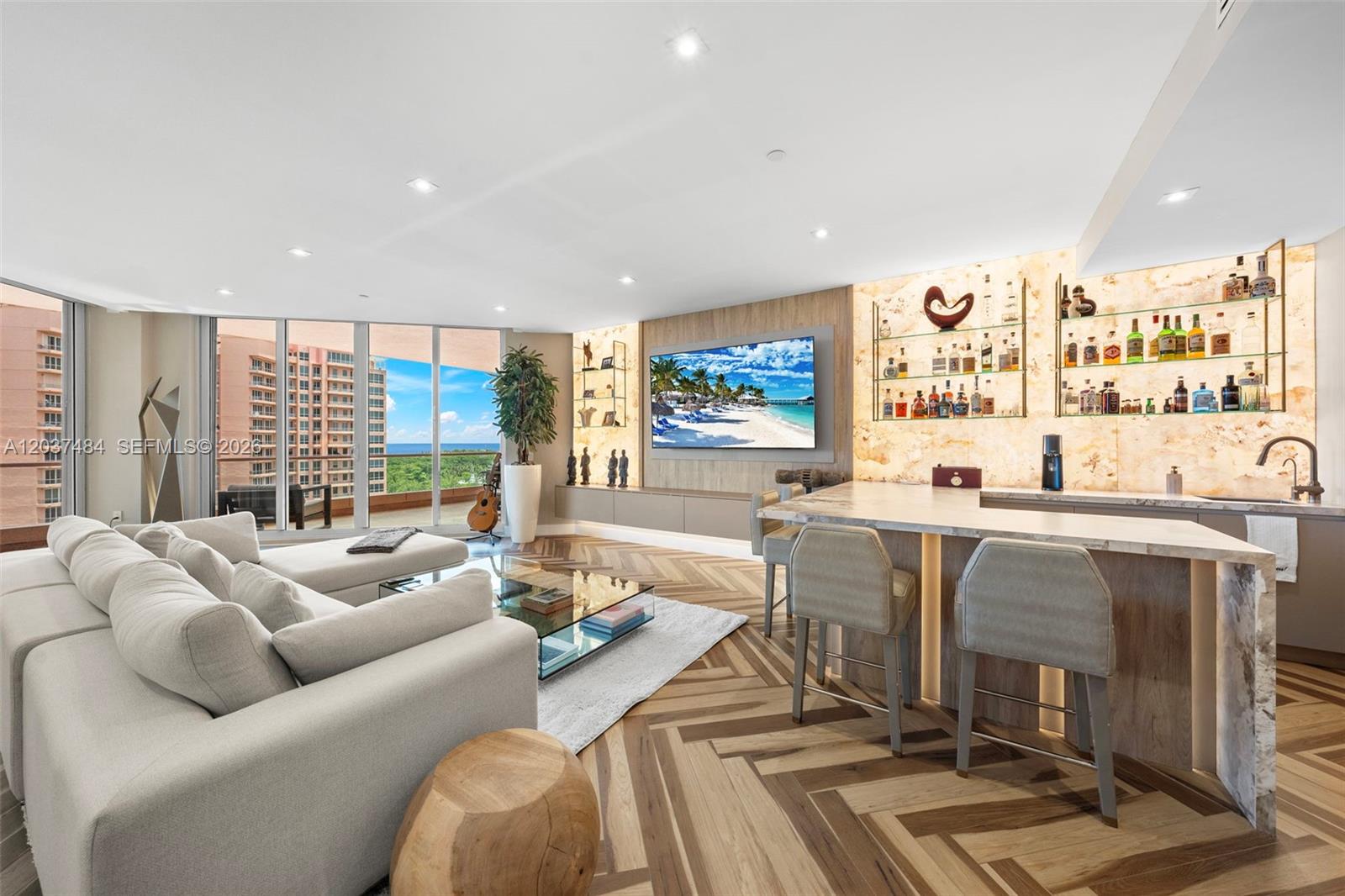 A modern living room features a bar area, herringbone wood floors, and floor-to-ceiling windows — 60 Edgewater Dr # 11F, Coral Gables FL 33133, CORAL GABLES, FL