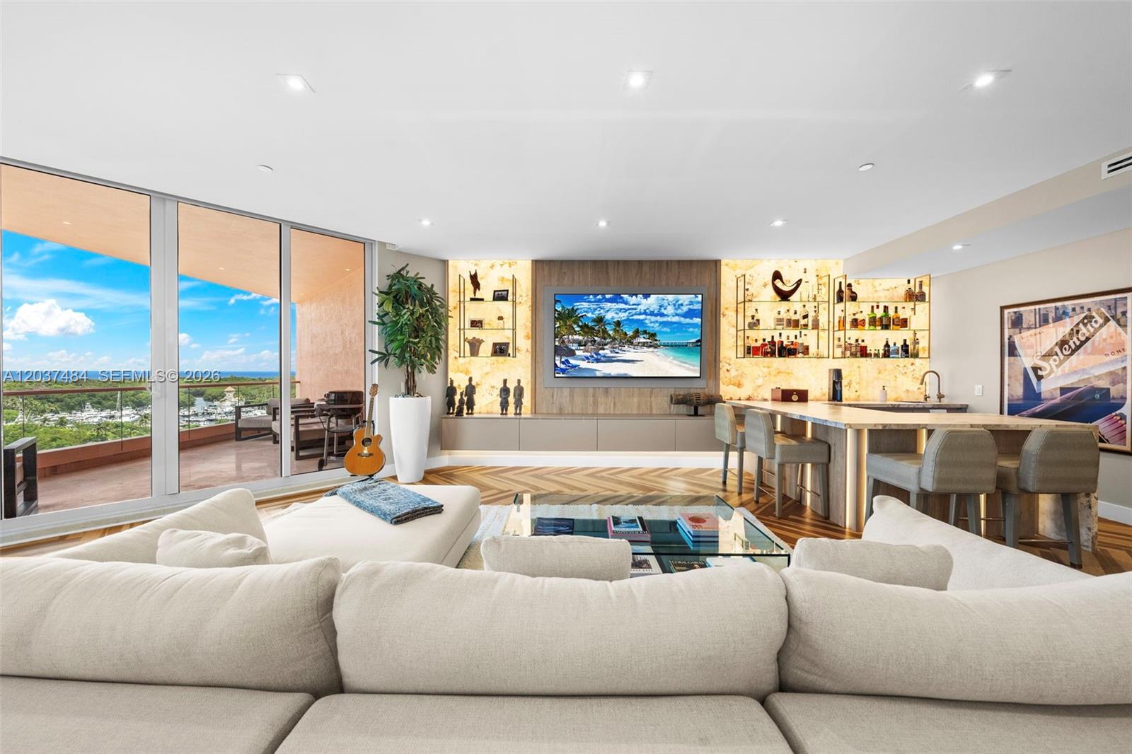 A living room features a large sectional sofa, a built-in media wall, and a home bar — 60 Edgewater Dr # 11F, Coral Gables FL 33133, CORAL GABLES, FL