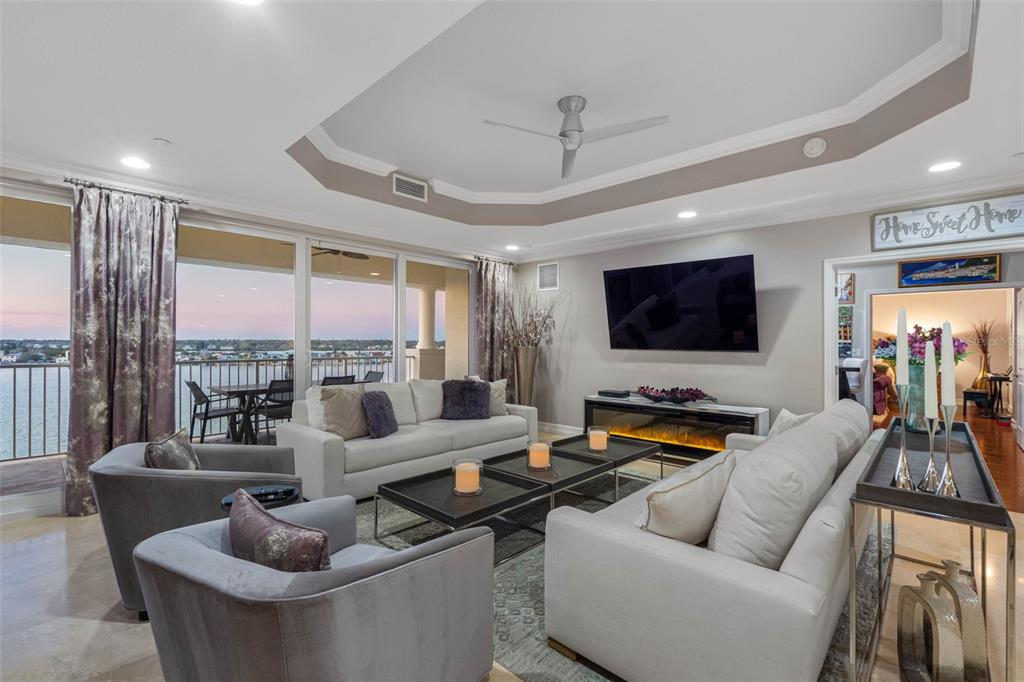 A living room features a tray ceiling, a fireplace, and a balcony overlooking the water — 17717 GULF BOULEVARD UNIT 702, REDINGTON SHORES, FL