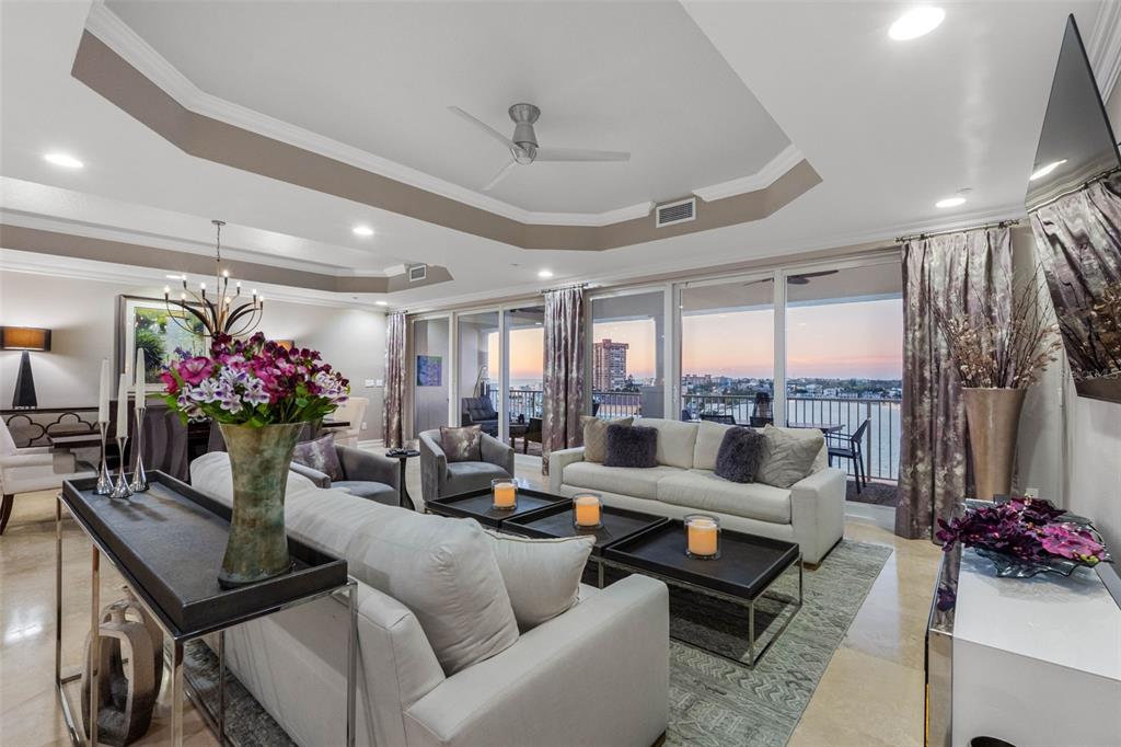 A spacious open-concept living and dining area features tile floors, a chandelier, and balcony views — 17717 GULF BOULEVARD UNIT 702, REDINGTON SHORES, FL