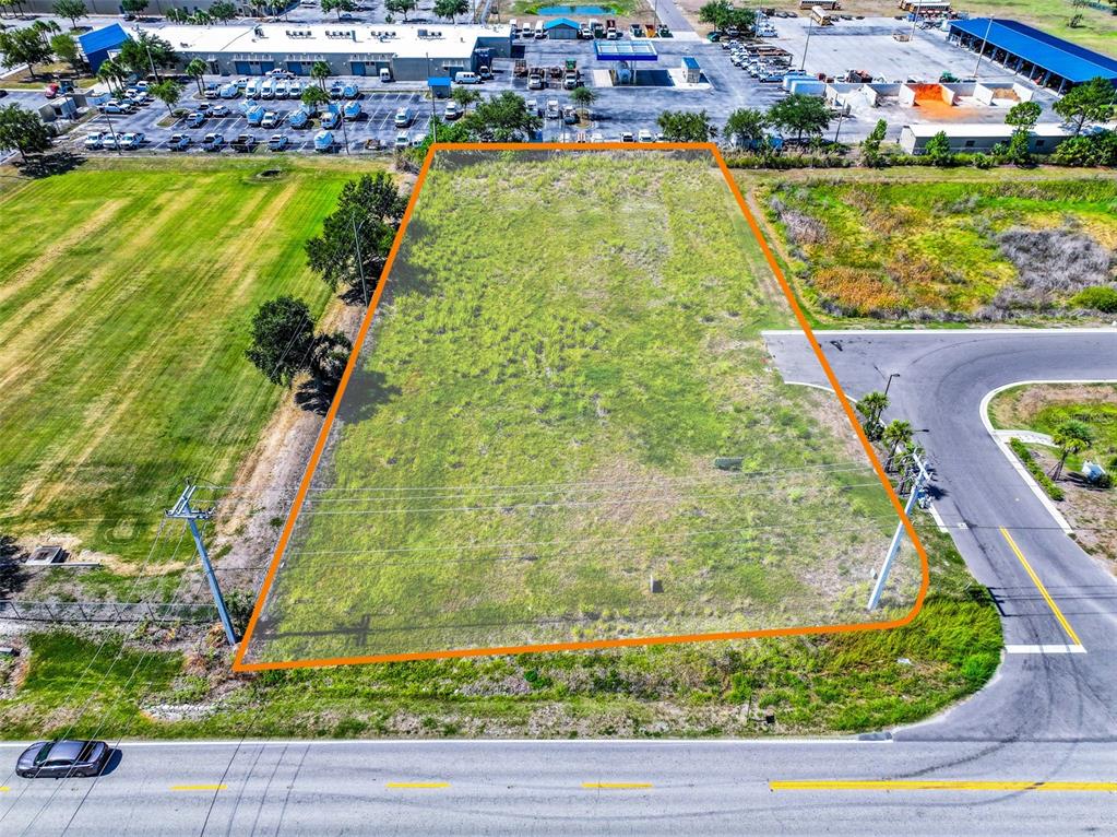 An aerial view shows a rectangular vacant lot outlined in orange next to a road — 2814 26TH AVENUE E, BRADENTON, FL