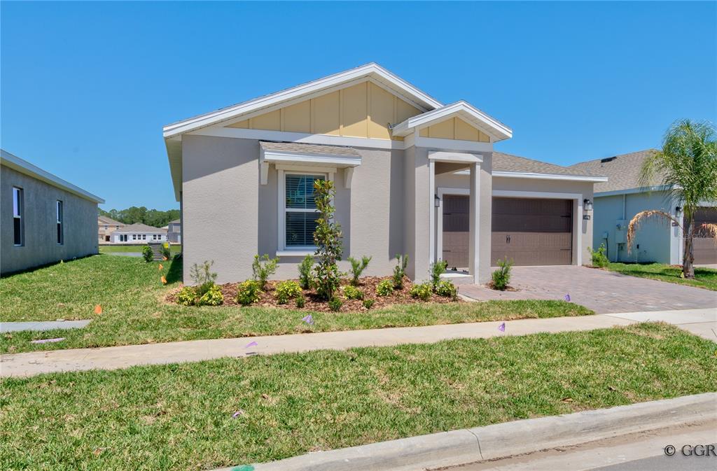 A single-story house with a beige stucco exterior, a two-car garage, and a front lawn — 1496 BRENTWOOD DRIVE, KISSIMMEE, FL