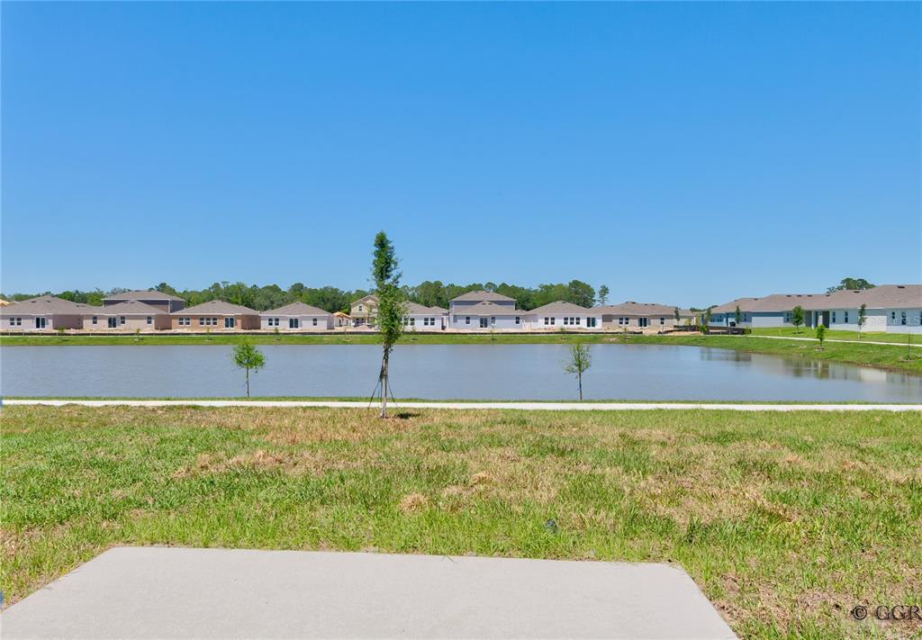 A view of a pond behind a grassy yard with houses in the background — 1496 BRENTWOOD DRIVE, KISSIMMEE, FL