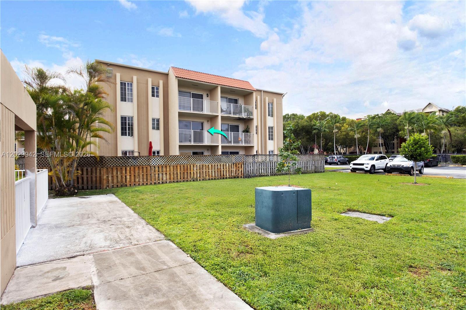 An exterior view of a three-story apartment building with balconies and a grassy yard — DORAL, FL