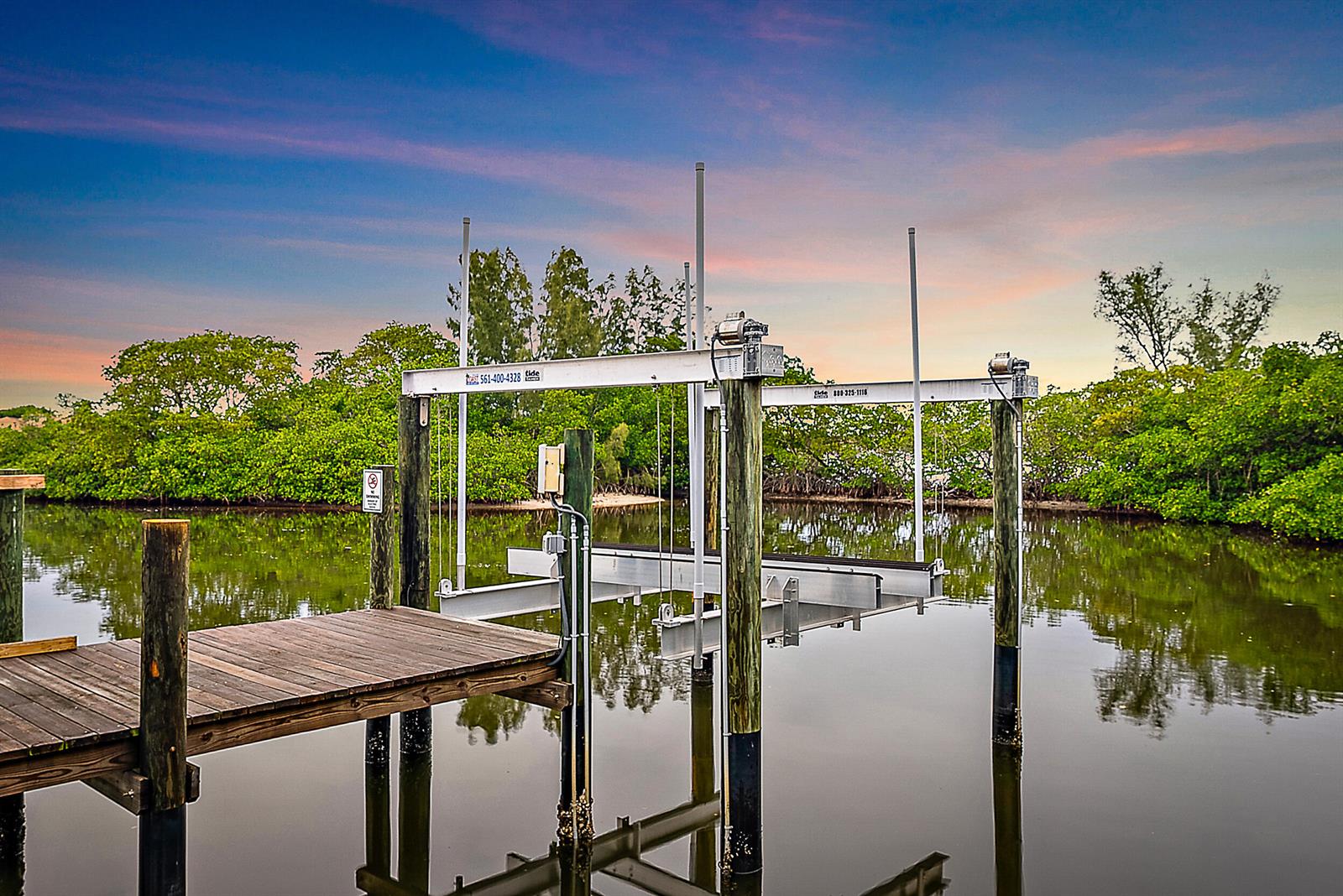 A boat lift stands over calm water next to a wooden dock at sunset — 18189 49th Terrace, Jupiter FL 33458, JUPITER, FL