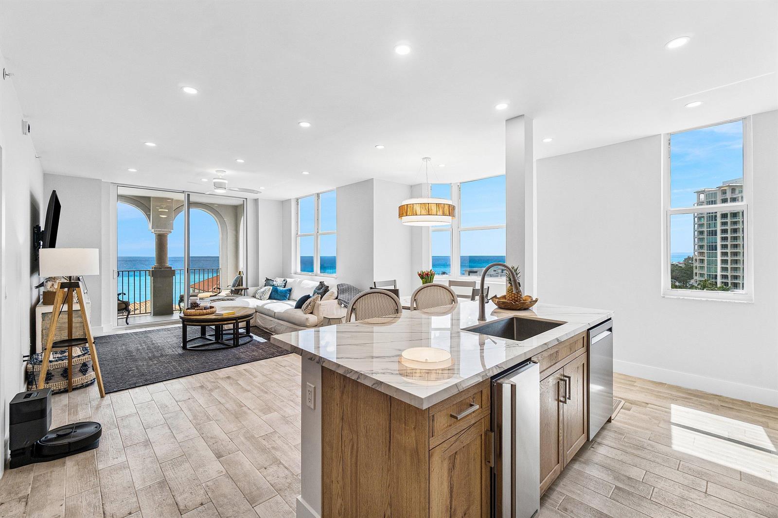 A modern kitchen island with marble countertops overlooks an open living area with ocean views — 3606 S Ocean 1002 Boulevard # 1002, Highland Beach FL 33487, HIGHLAND BEACH, FL