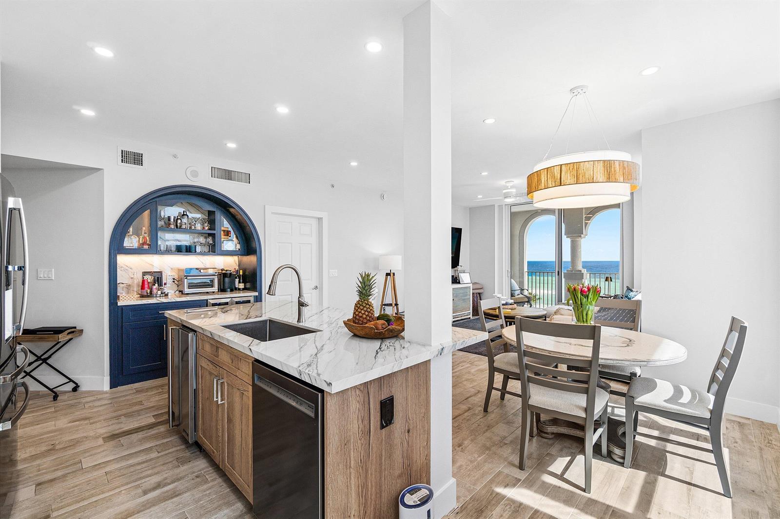 A kitchen with a marble island and blue arched bar area overlooks a dining space — 3606 S Ocean 1002 Boulevard # 1002, Highland Beach FL 33487, HIGHLAND BEACH, FL