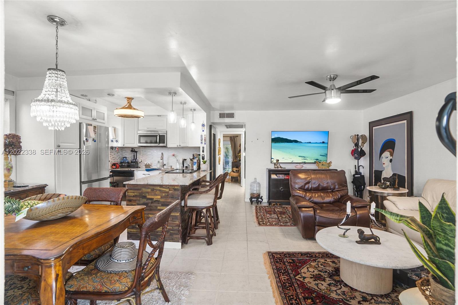 An open-concept living and dining area features a kitchen island, tile flooring, and ceiling fans — 181 Lyndhurst L # 181, Deerfield Beach FL 33442, DEERFIELD BEACH, FL