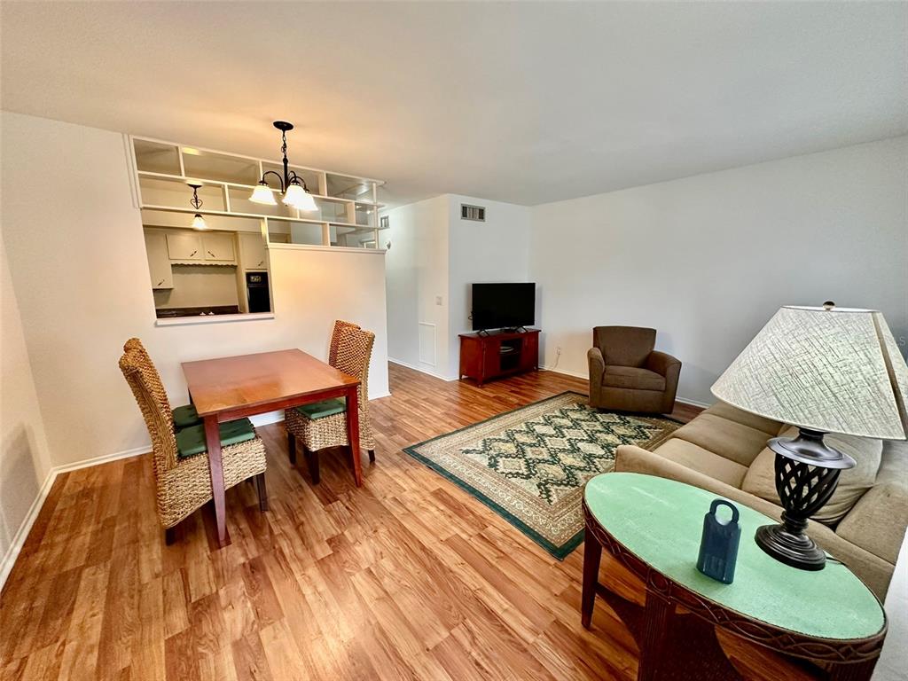 A living and dining area features wood-look flooring, a pass-through window, and a ceiling light — 2100 WORLD PARKWAY BOULEVARD UNIT 50, CLEARWATER, FL