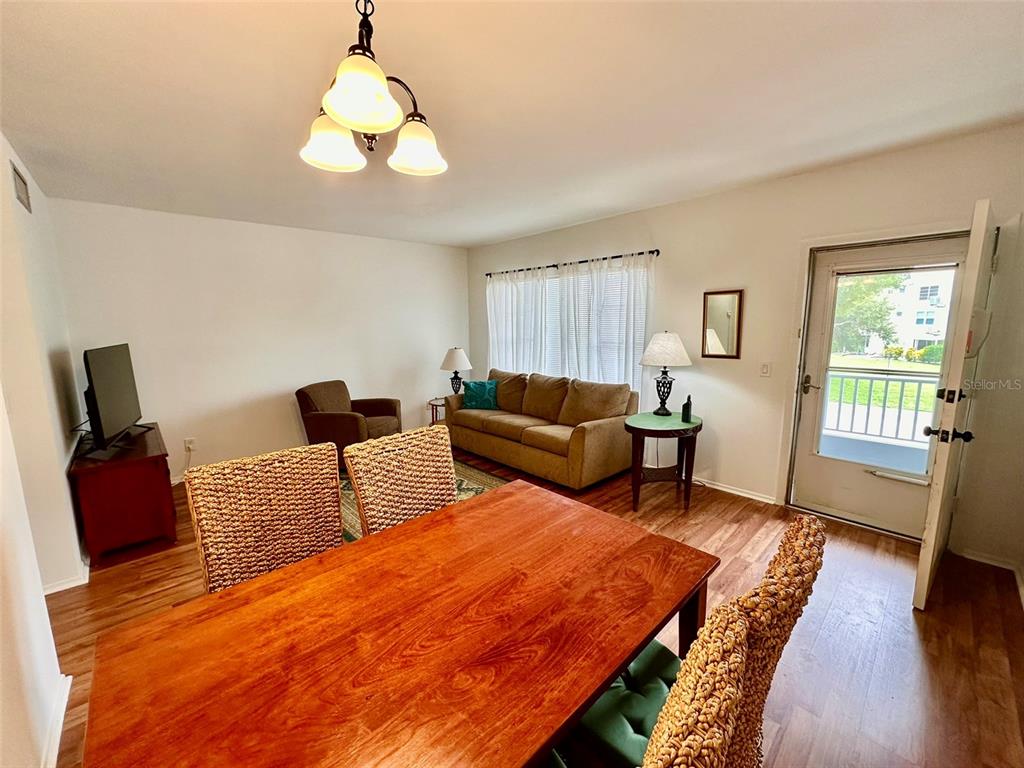 A living and dining area features wood-look flooring, a brown sofa, and a wooden table — 2100 WORLD PARKWAY BOULEVARD UNIT 50, CLEARWATER, FL