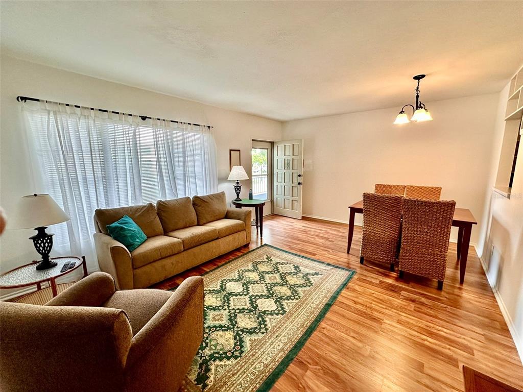 A living and dining area with wood flooring, a patterned rug, and a tan sofa — 2100 WORLD PARKWAY BOULEVARD UNIT 50, CLEARWATER, FL
