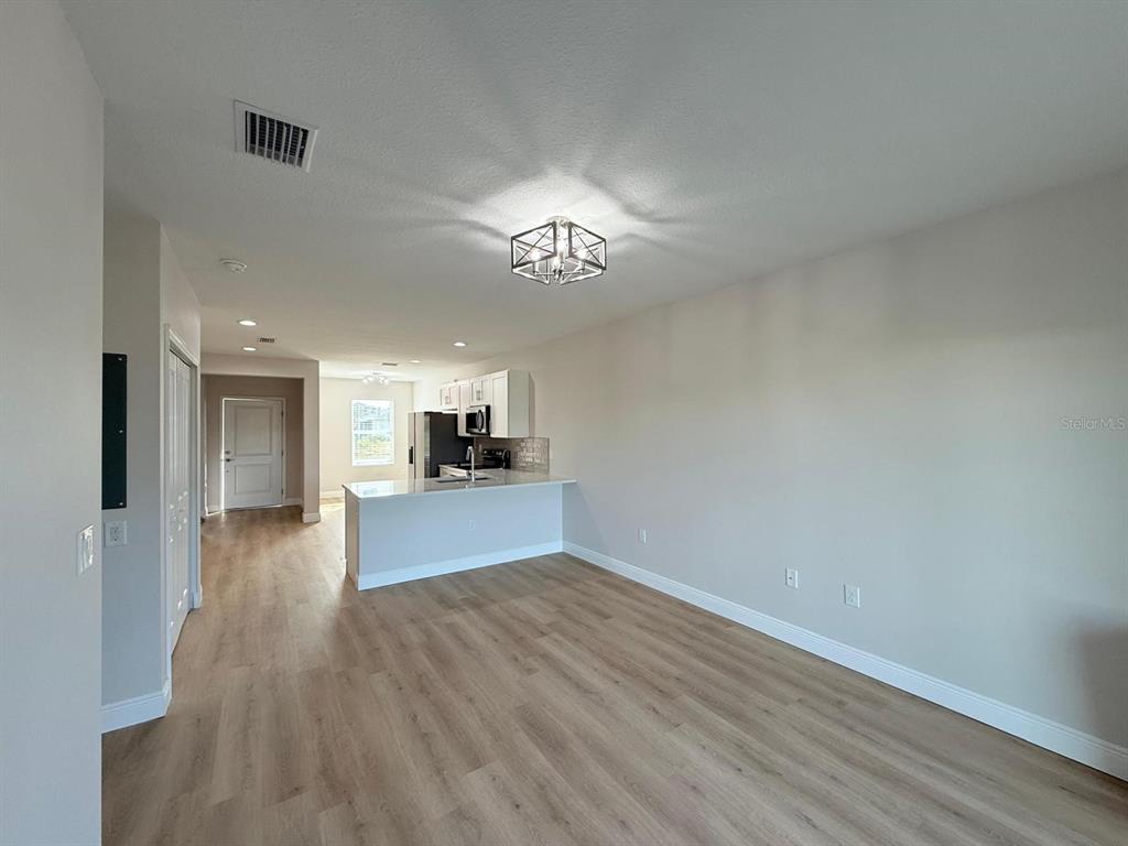An open-concept living area features light wood-look flooring, a kitchen island, and a modern light fixture — 10336 PENDLETON AVENUE, ENGLEWOOD, FL