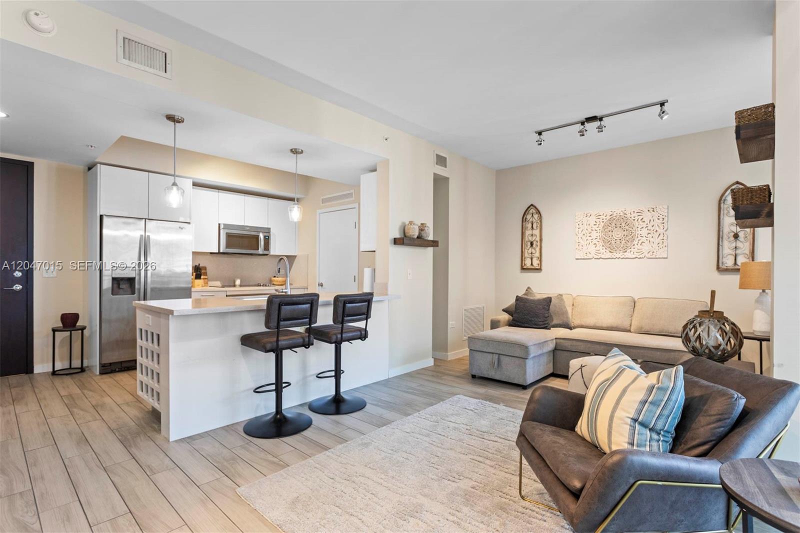 An open-concept living room and kitchen area features light wood flooring and modern furniture — 999 SW 1st Ave # 2015, Miami FL 33130, MIAMI, FL