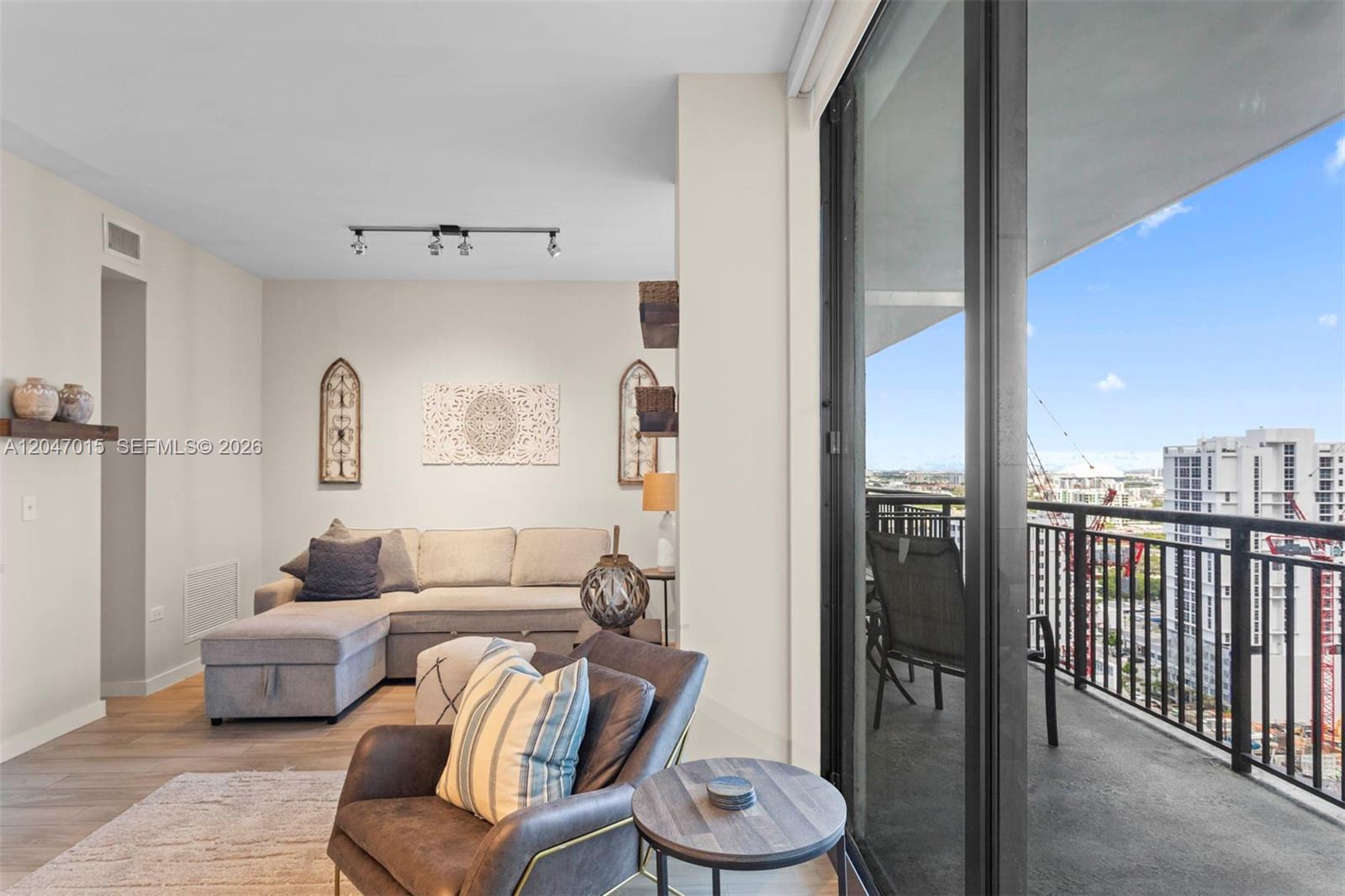 A living room with a sectional sofa, an armchair, and a balcony overlooking city buildings — 999 SW 1st Ave # 2015, Miami FL 33130, MIAMI, FL
