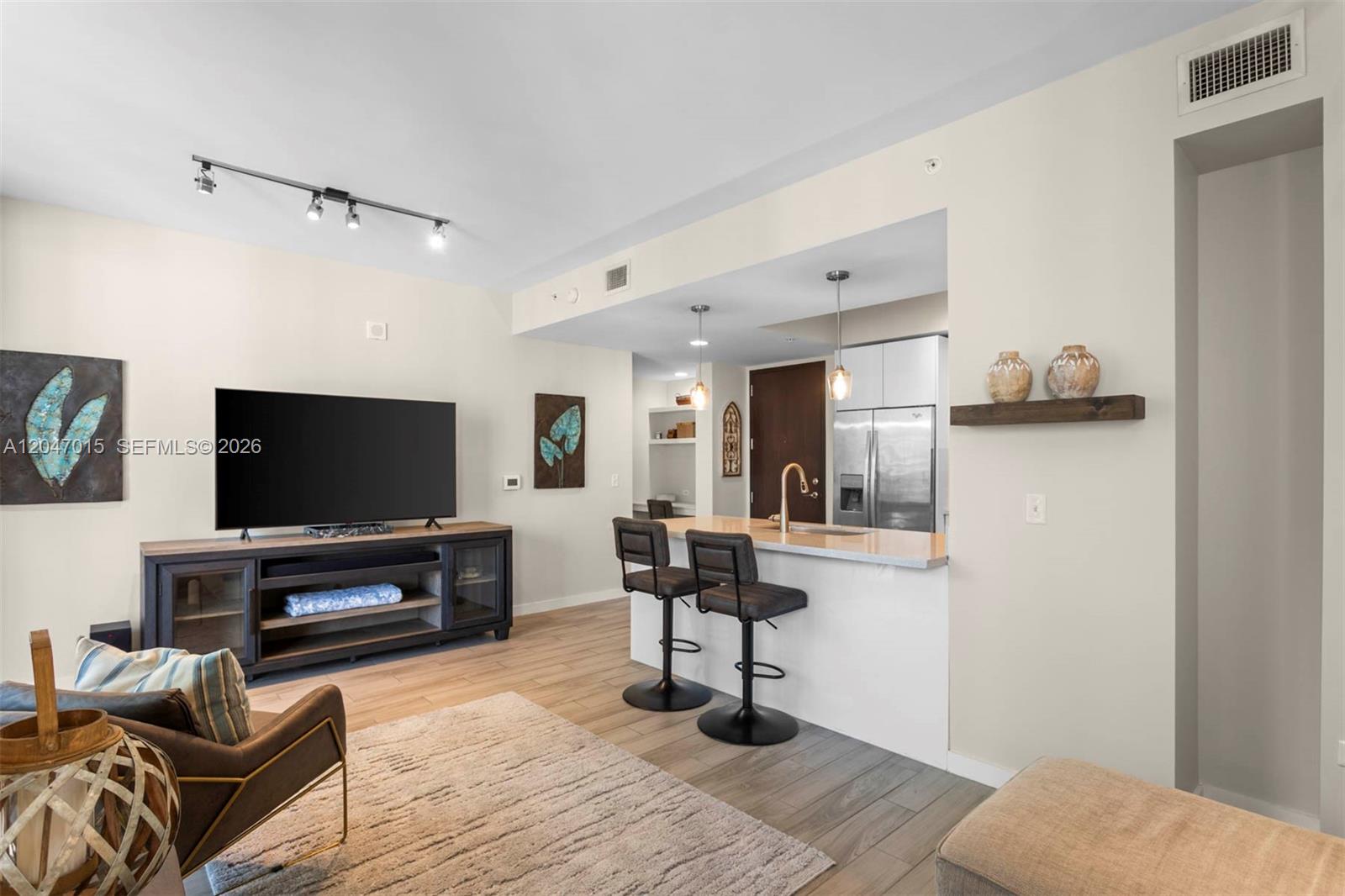 A living room features a television console, breakfast bar with stools, and wood-look flooring — 999 SW 1st Ave # 2015, Miami FL 33130, MIAMI, FL