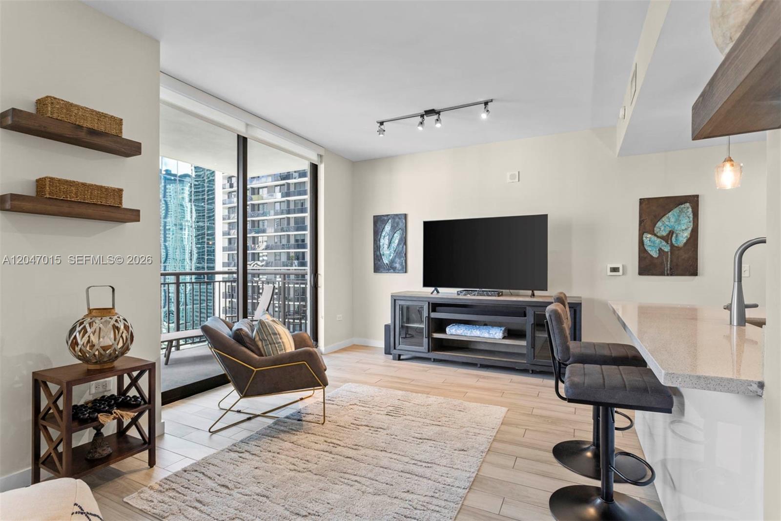 A living room features a television console, an armchair, bar stools, and a balcony view — 999 SW 1st Ave # 2015, Miami FL 33130, MIAMI, FL
