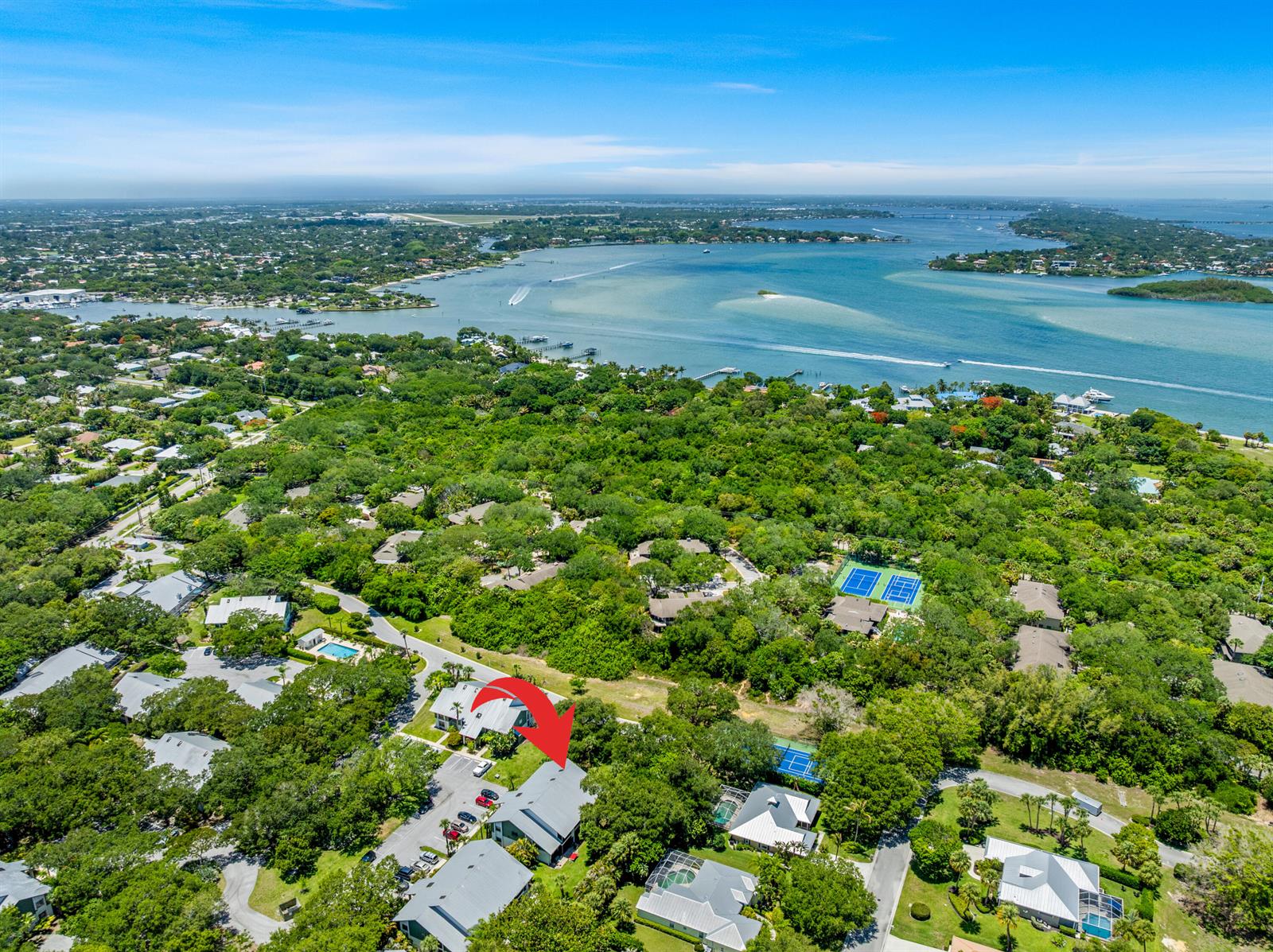 An aerial view shows a residential complex surrounded by dense trees near a large bay — 5280 SE Seascape Way # 101, Stuart FL 34997, STUART, FL