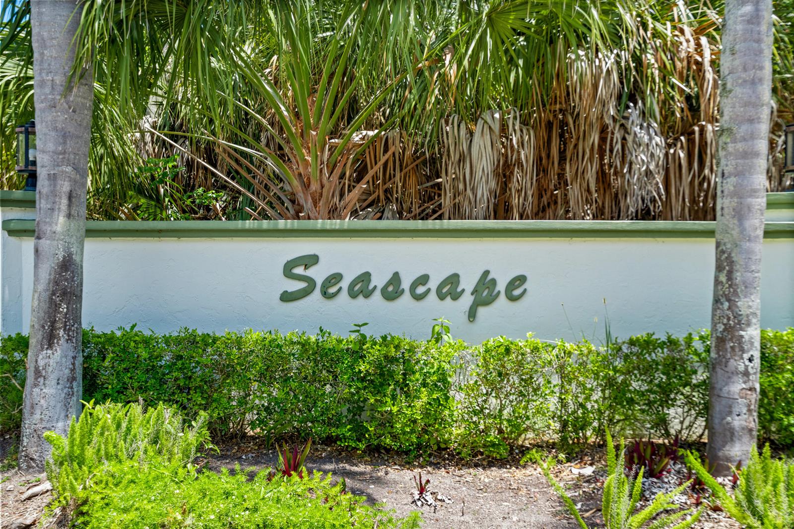 A white stucco wall with the word Seascape in green letters stands behind green hedges — 5280 SE Seascape Way # 101, Stuart FL 34997, STUART, FL