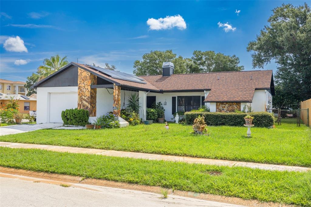 A single-story house with a white exterior, stone accents, and a brown shingled roof — 1338 GREENLEA DRIVE, HOLIDAY, FL