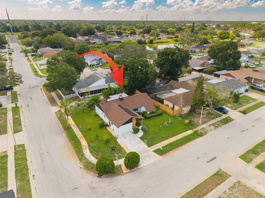An aerial view shows a single-story house with a brown roof on a corner lot — 1338 GREENLEA DRIVE, HOLIDAY, FL