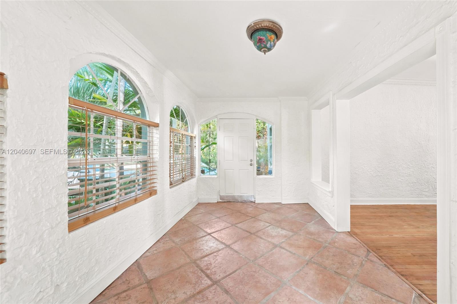 A sunroom features white textured walls, terracotta tile flooring, arched windows, and a floral light fixture — 160 NE 44th St # 1, Miami FL 33137, MIAMI, FL