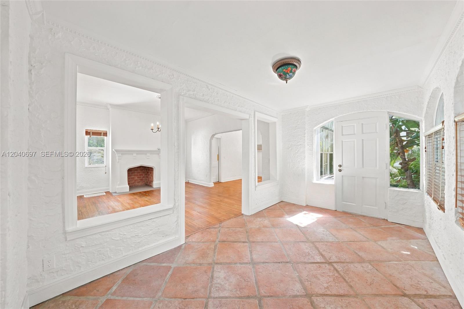 A bright entryway with terracotta tile flooring, white textured walls, and a view of a fireplace — 160 NE 44th St # 1, Miami FL 33137, MIAMI, FL