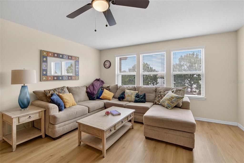 A living room features a large beige sectional sofa, a coffee table, and three windows — 6207 MAGNOLIA PARK BLVD, RIVERVIEW, FL