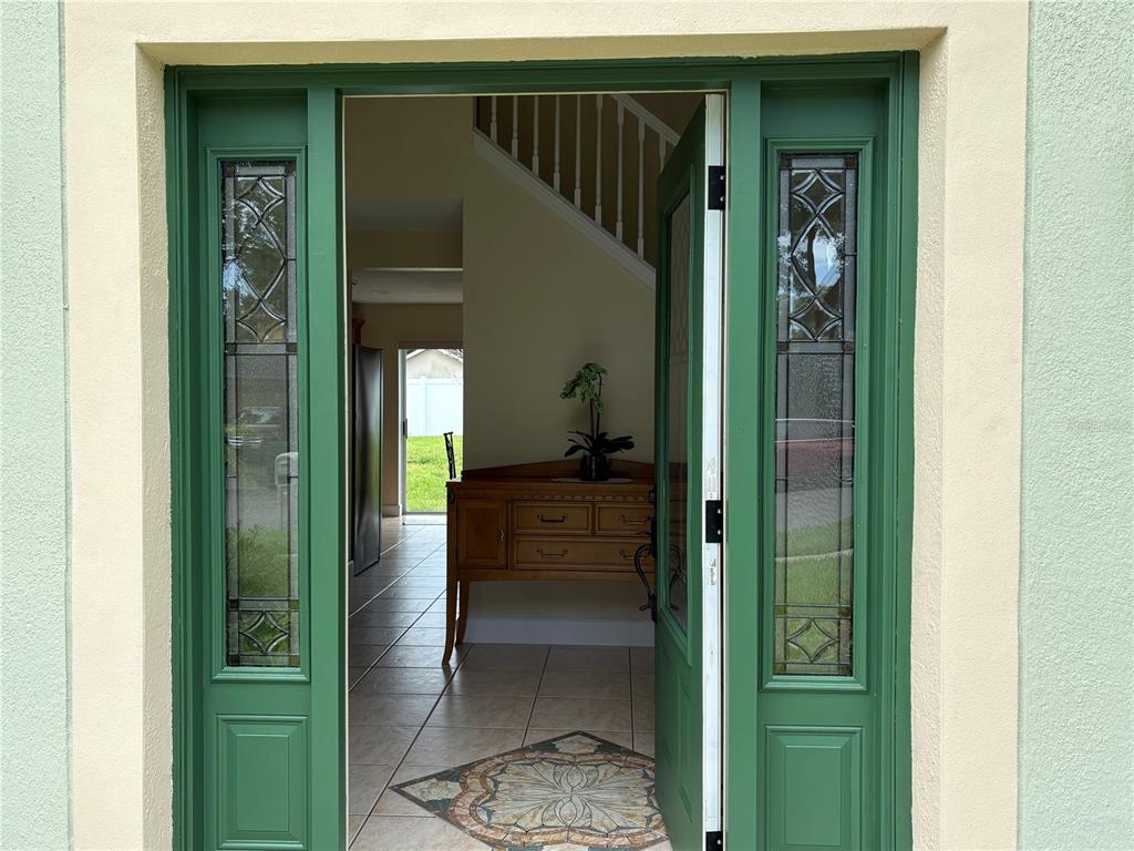 An open green front door with sidelights reveals an entryway with tile flooring and stairs — 1072 ROYAL MARQUIS CIRCLE, OCOEE, FL