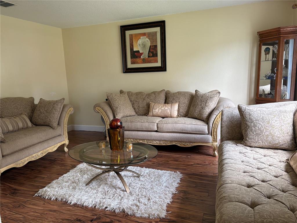 A living room features beige upholstered sofas, a glass coffee table, and wood-look flooring — 1072 ROYAL MARQUIS CIRCLE, OCOEE, FL