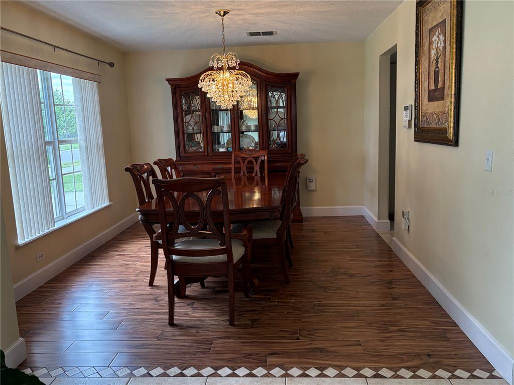 A dining room features a wood table, matching chairs, a hutch, and wood-look tile flooring — 1072 ROYAL MARQUIS CIRCLE, OCOEE, FL