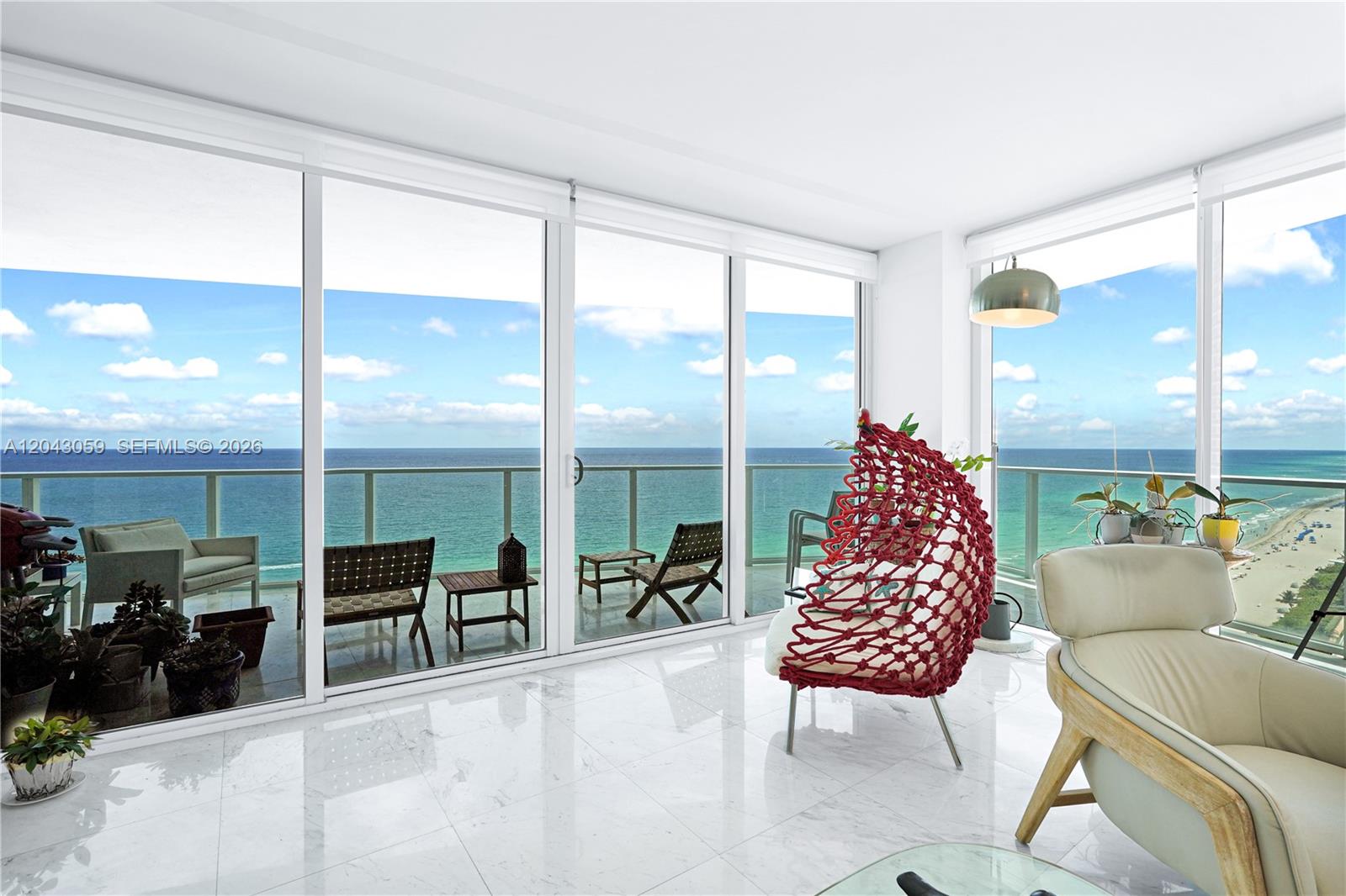 A bright living room features white marble floors, floor-to-ceiling windows, and a balcony overlooking the ocean — 3951 S Ocean Dr # 1901, Hollywood FL 33019, HOLLYWOOD, FL