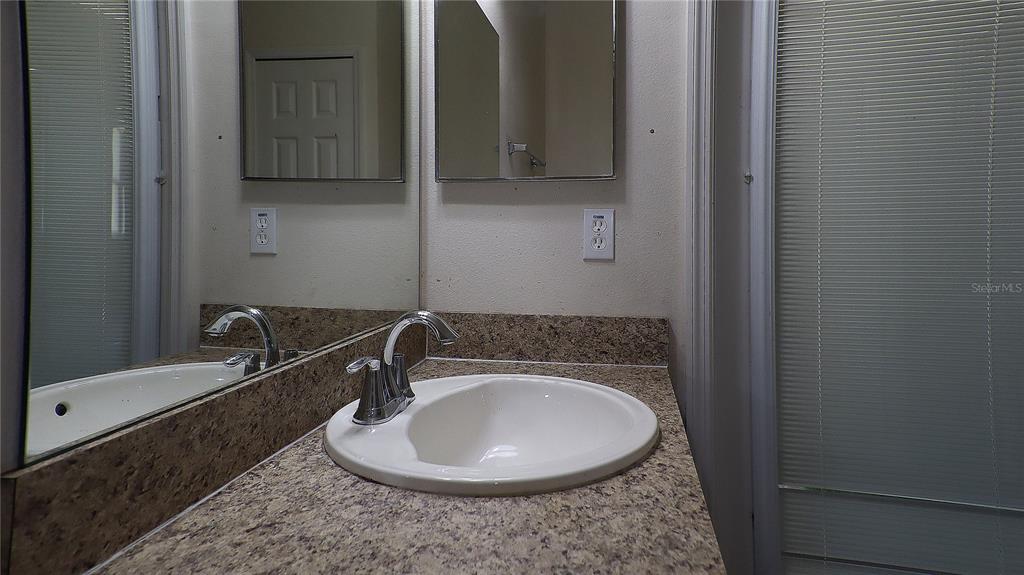 A spacious room features light blue walls, wood-look flooring, a ceiling fan, and a projector screen — 3114 NE 24TH PLACE, OCALA, FL