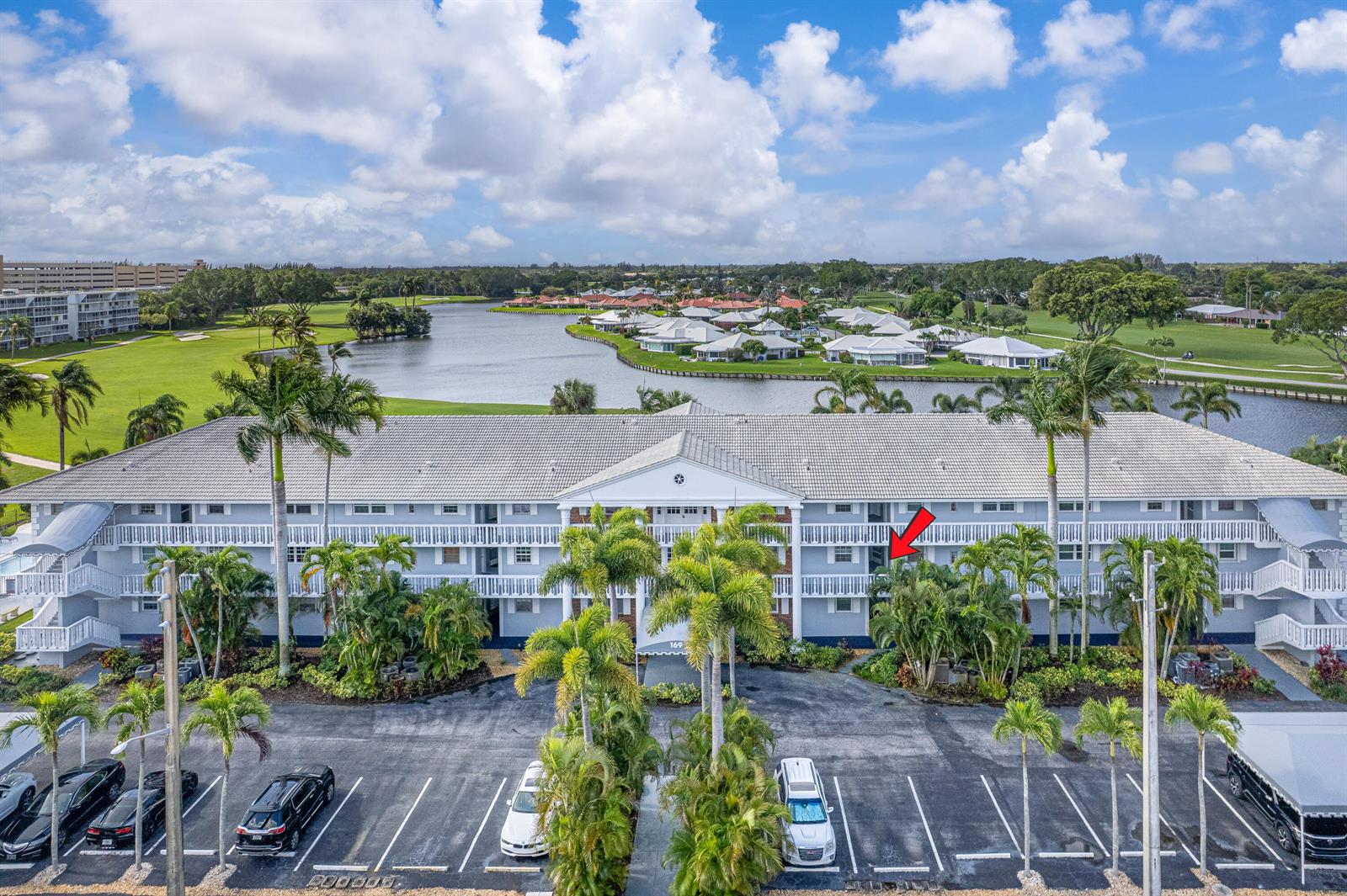 An aerial view shows a multi-story apartment building situated beside a lake and golf course — 169 Atlantis Boulevard # 205, Atlantis FL 33462, ATLANTIS, FL