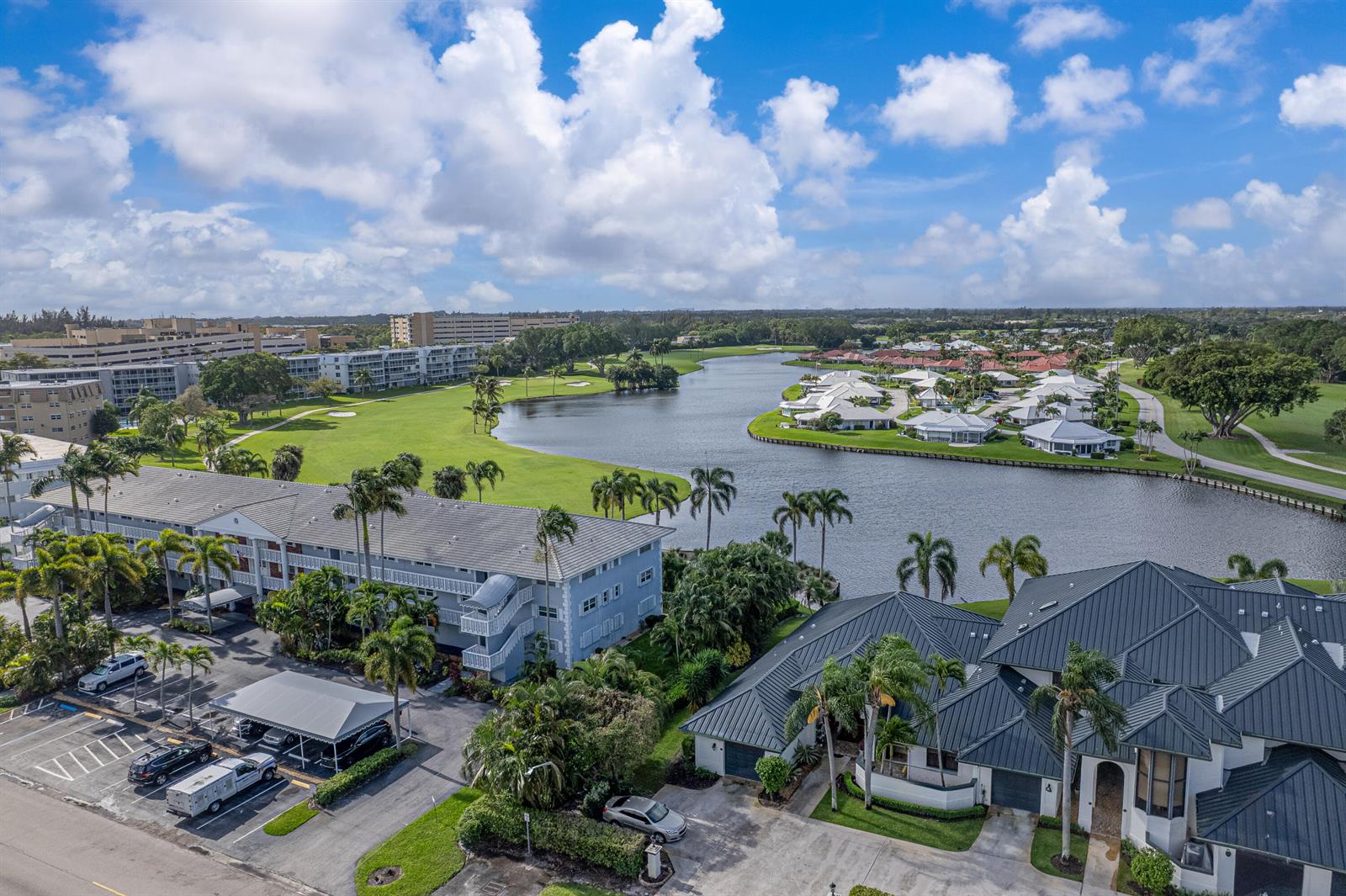 An exterior view of a multi-story apartment building with a parking lot and lake — 169 Atlantis Boulevard # 205, Atlantis FL 33462, ATLANTIS, FL