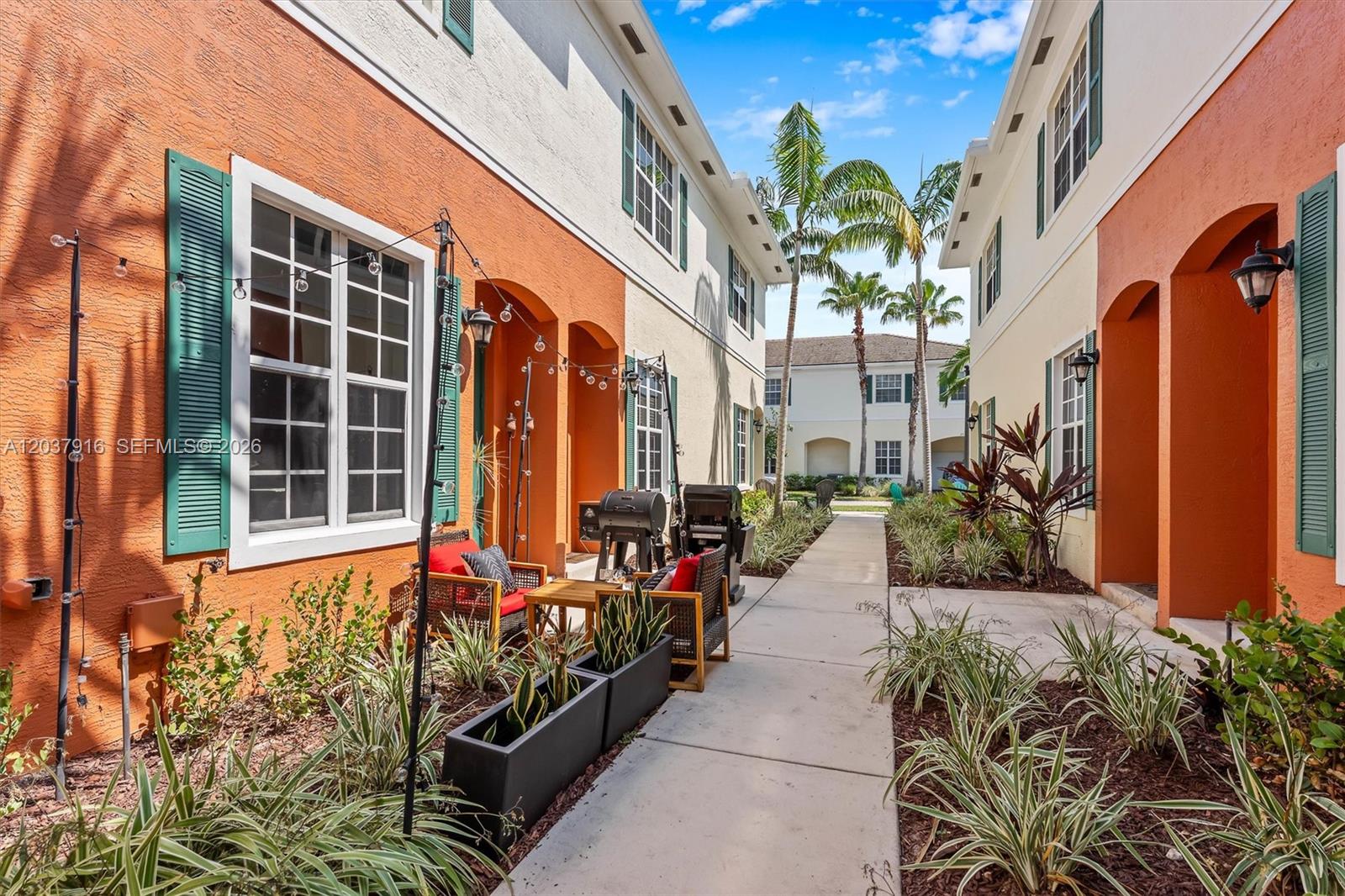 An outdoor walkway between two-story residential buildings with orange and cream stucco walls — 712 SW 2nd Way # 712, Pompano Beach FL 33060, POMPANO BEACH, FL