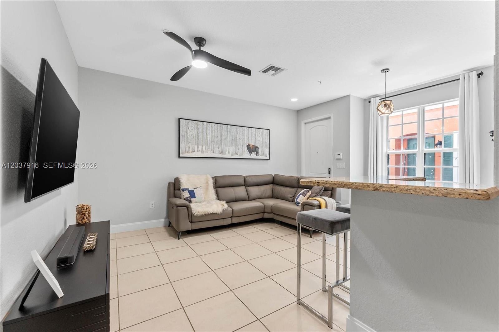 A living room features a gray sectional sofa, tiled floors, and a breakfast bar — 712 SW 2nd Way # 712, Pompano Beach FL 33060, POMPANO BEACH, FL