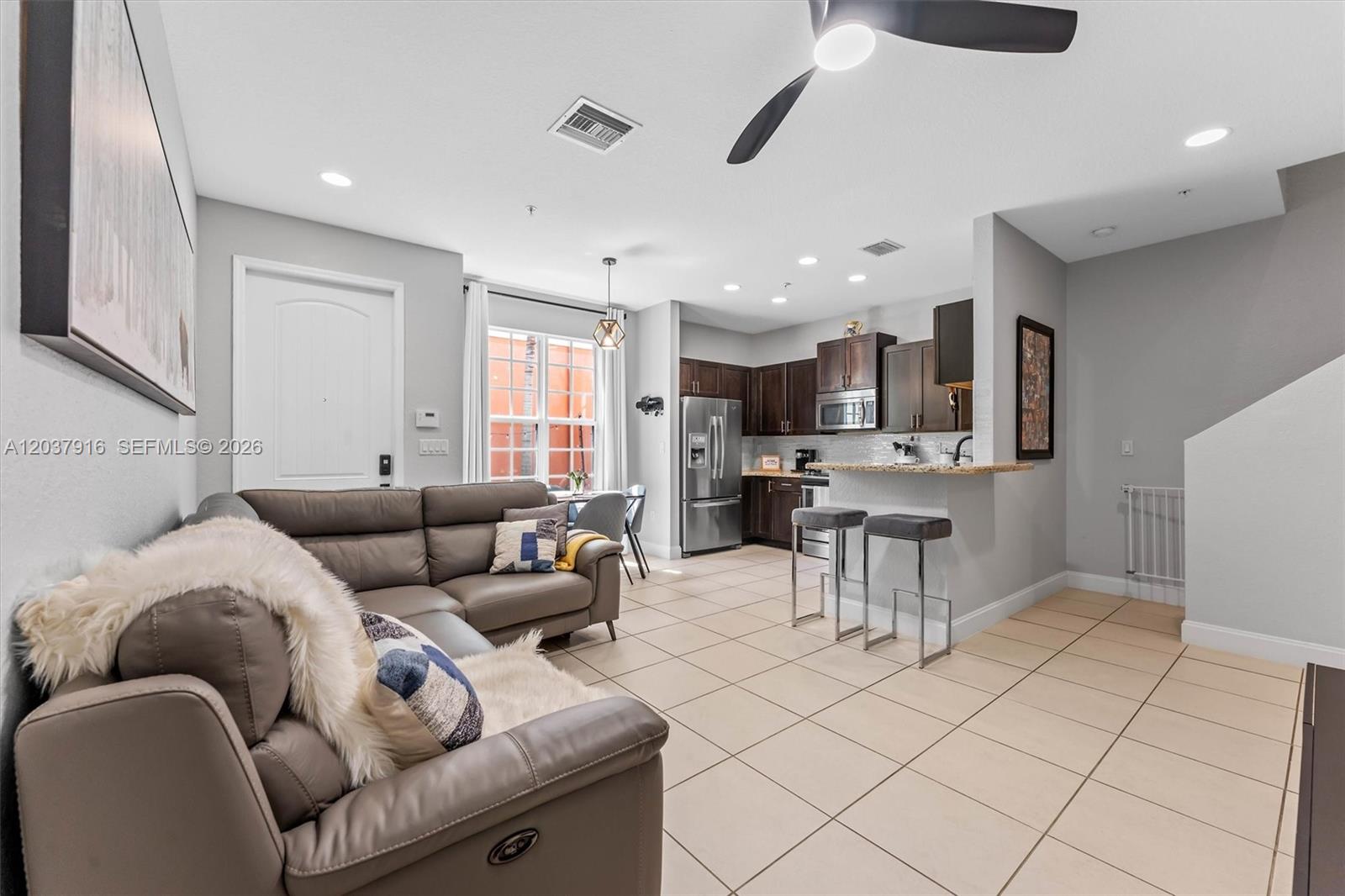 A living room with a grey sectional sofa opens into a kitchen with bar seating — 712 SW 2nd Way # 712, Pompano Beach FL 33060, POMPANO BEACH, FL