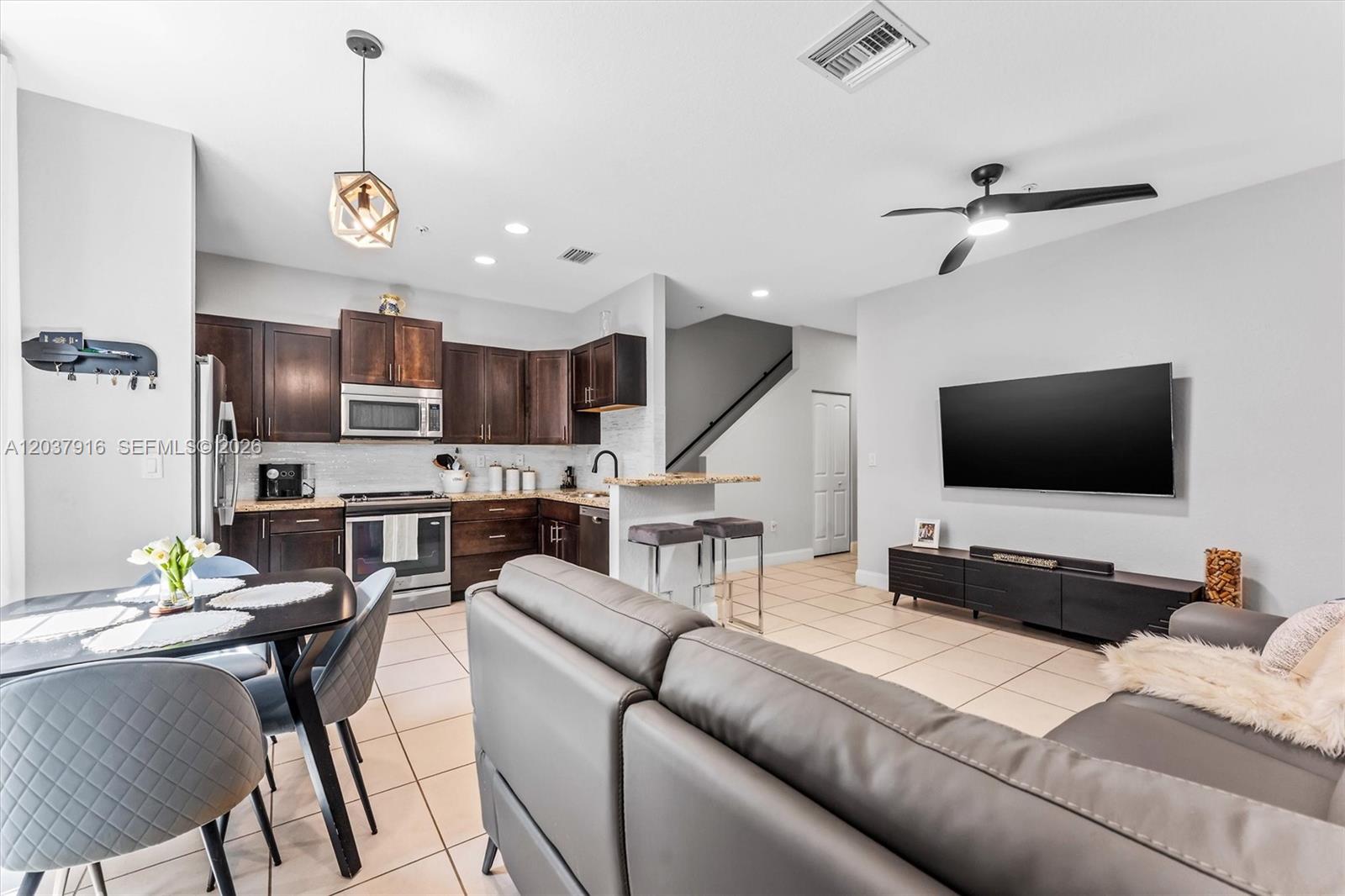 An open-concept living room and kitchen with dark wood cabinets and gray leather furniture — 712 SW 2nd Way # 712, Pompano Beach FL 33060, POMPANO BEACH, FL