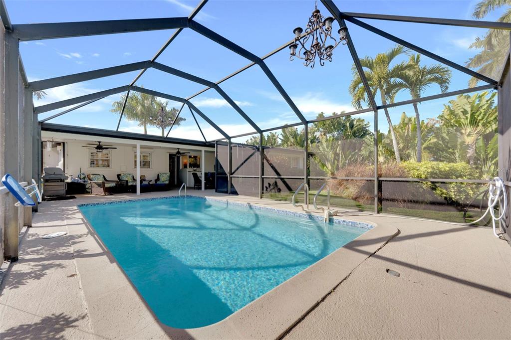 A screened-in swimming pool area with a covered patio and a hanging chandelier — 14526 RIVERSIDE DRIVE, FORT MYERS, FL