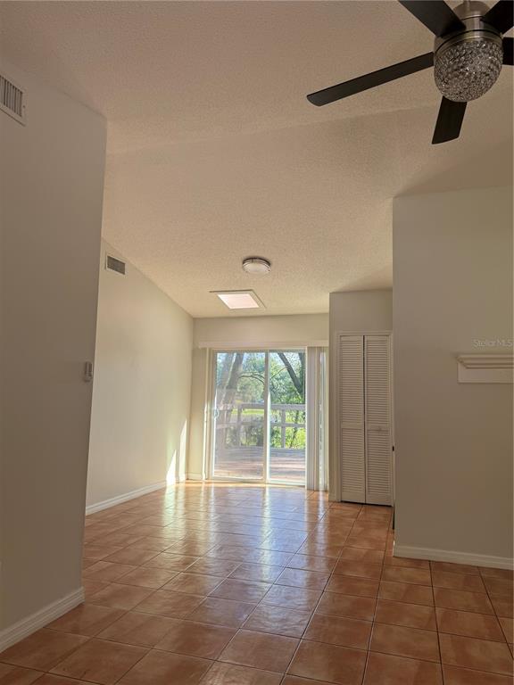 A living room with vaulted ceilings, tile flooring, a ceiling fan, and sliding glass doors — 7320 ANSTEAD CIRCLE, ORLANDO, FL