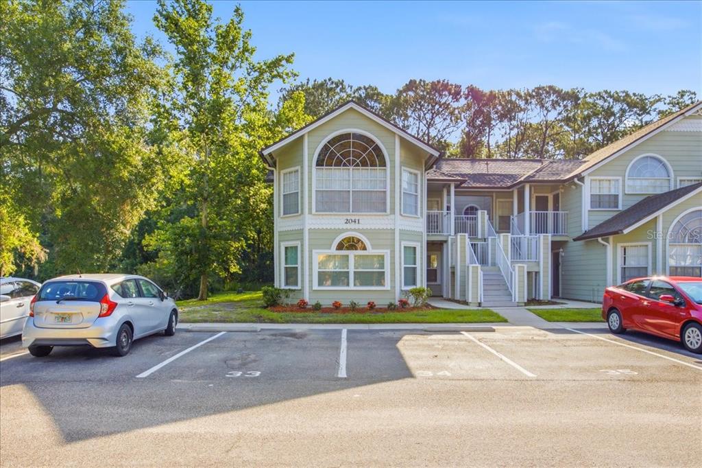 A two-story light green apartment building with a staircase leading to an upper balcony — 2041 ROYAL BAY BOULEVARD UNIT 33, KISSIMMEE, FL