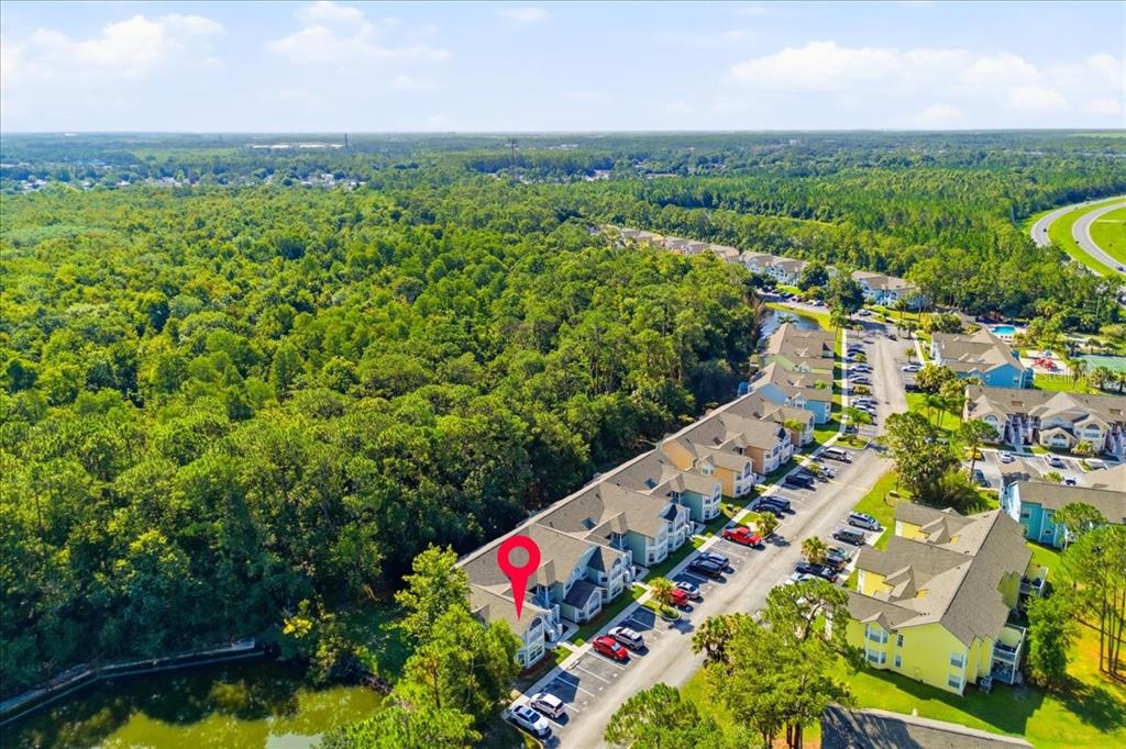 An aerial view shows a multi-story apartment complex surrounded by trees and a pond — 2041 ROYAL BAY BOULEVARD UNIT 33, KISSIMMEE, FL