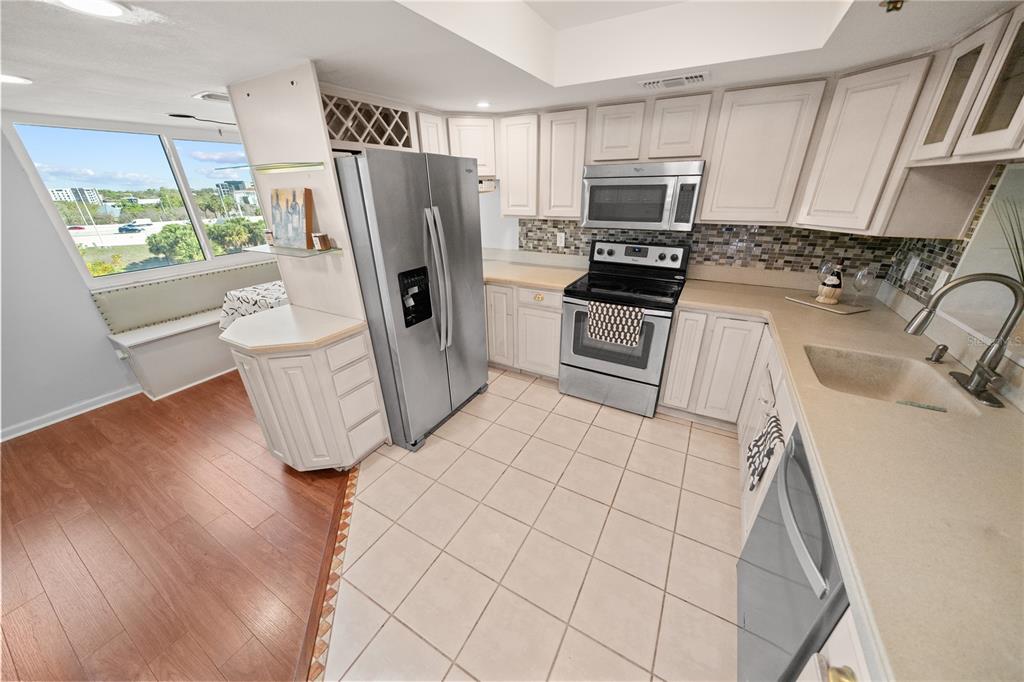 A kitchen with white cabinets, stainless steel appliances, tile flooring, and a window-side breakfast nook — 201 W LAUREL STREET UNIT 701, TAMPA, FL
