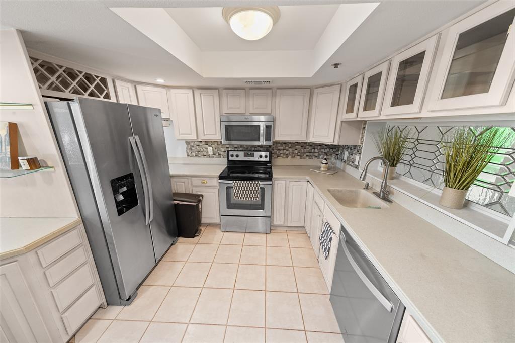 A kitchen featuring white cabinets, stainless steel appliances, tile flooring, and a recessed ceiling light — 201 W LAUREL STREET UNIT 701, TAMPA, FL
