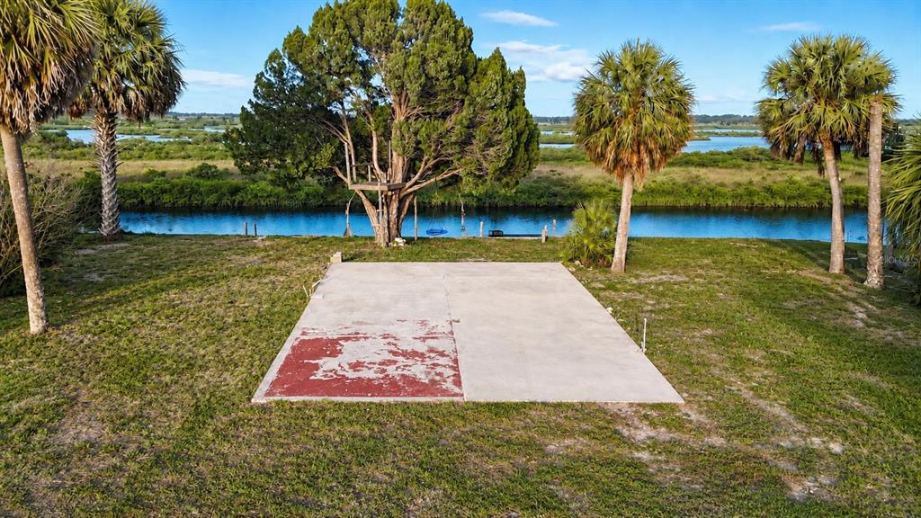 A concrete slab sits in a grassy yard overlooking a canal with palm trees nearby — 10166 CABANA STREET, WEEKI WACHEE, FL
