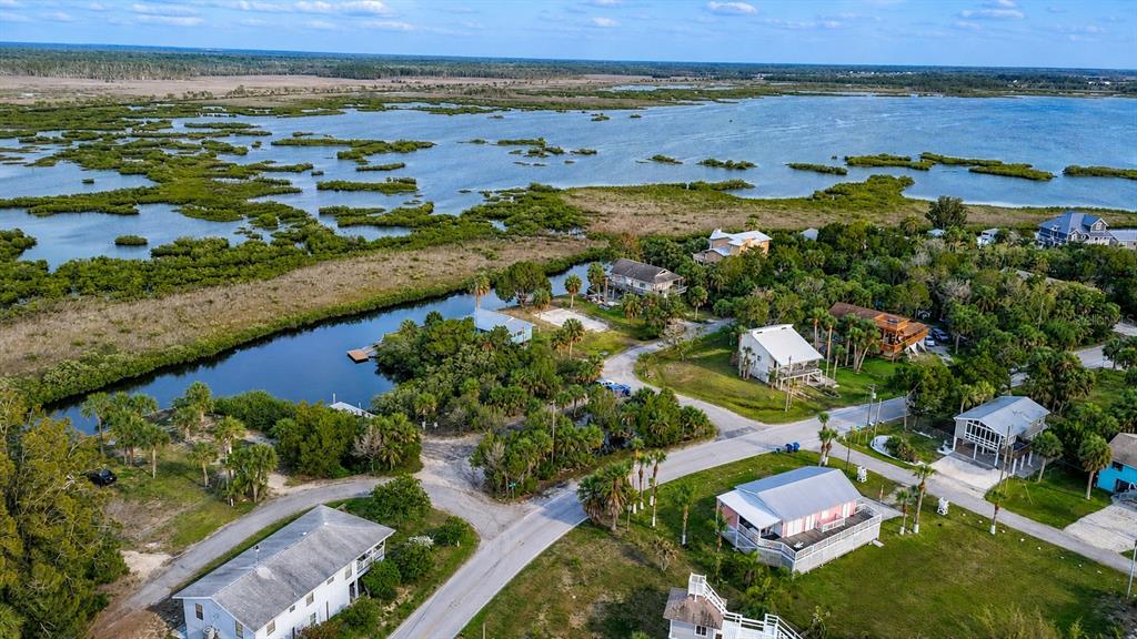 An aerial view shows houses situated along a coastal waterway surrounded by marshland and trees — 10166 CABANA STREET, WEEKI WACHEE, FL