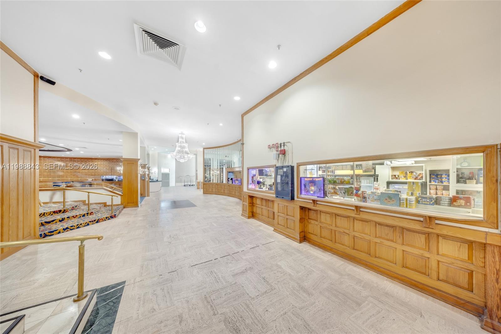 A hotel lobby features a snack bar, wood paneling, a chandelier, and a carpeted staircase — 5445 Collins Ave, Miami Beach FL 33140, MIAMI BEACH, FL