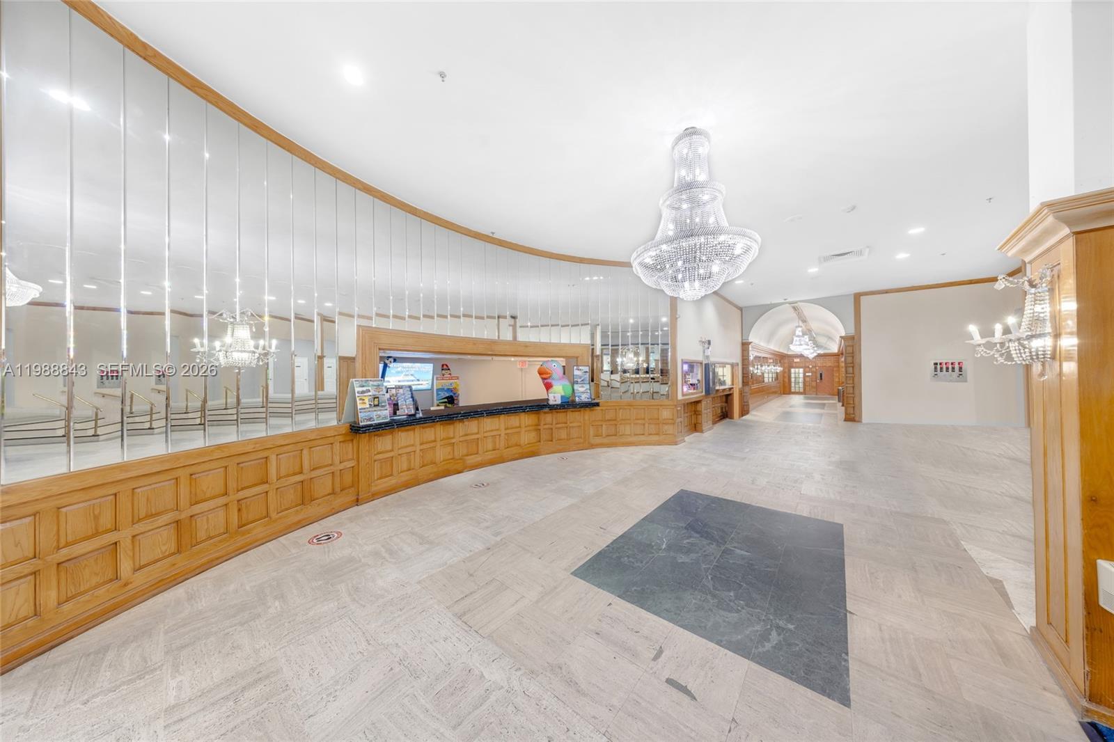 A lobby features a long wooden reception desk, mirrored walls, and a large crystal chandelier — 5445 Collins Ave, Miami Beach FL 33140, MIAMI BEACH, FL