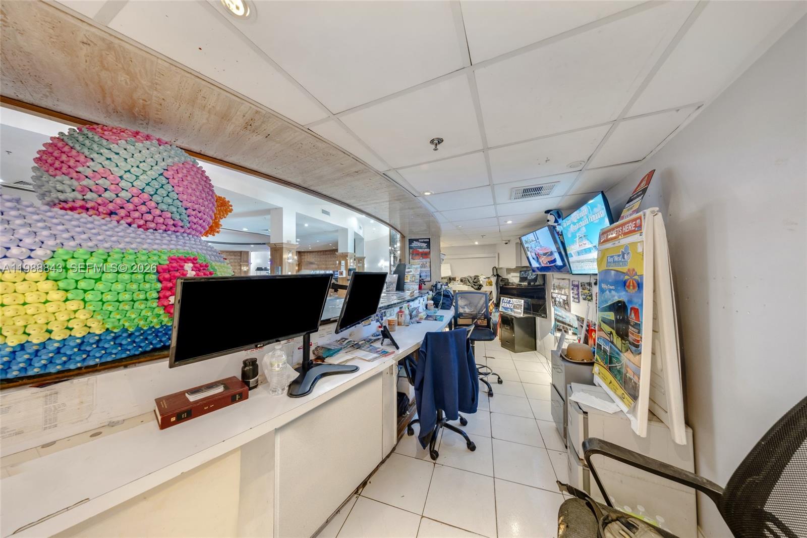 A commercial office space features a large decorative duck sculpture, computer monitors, and promotional signage — 5445 Collins Ave, Miami Beach FL 33140, MIAMI BEACH, FL