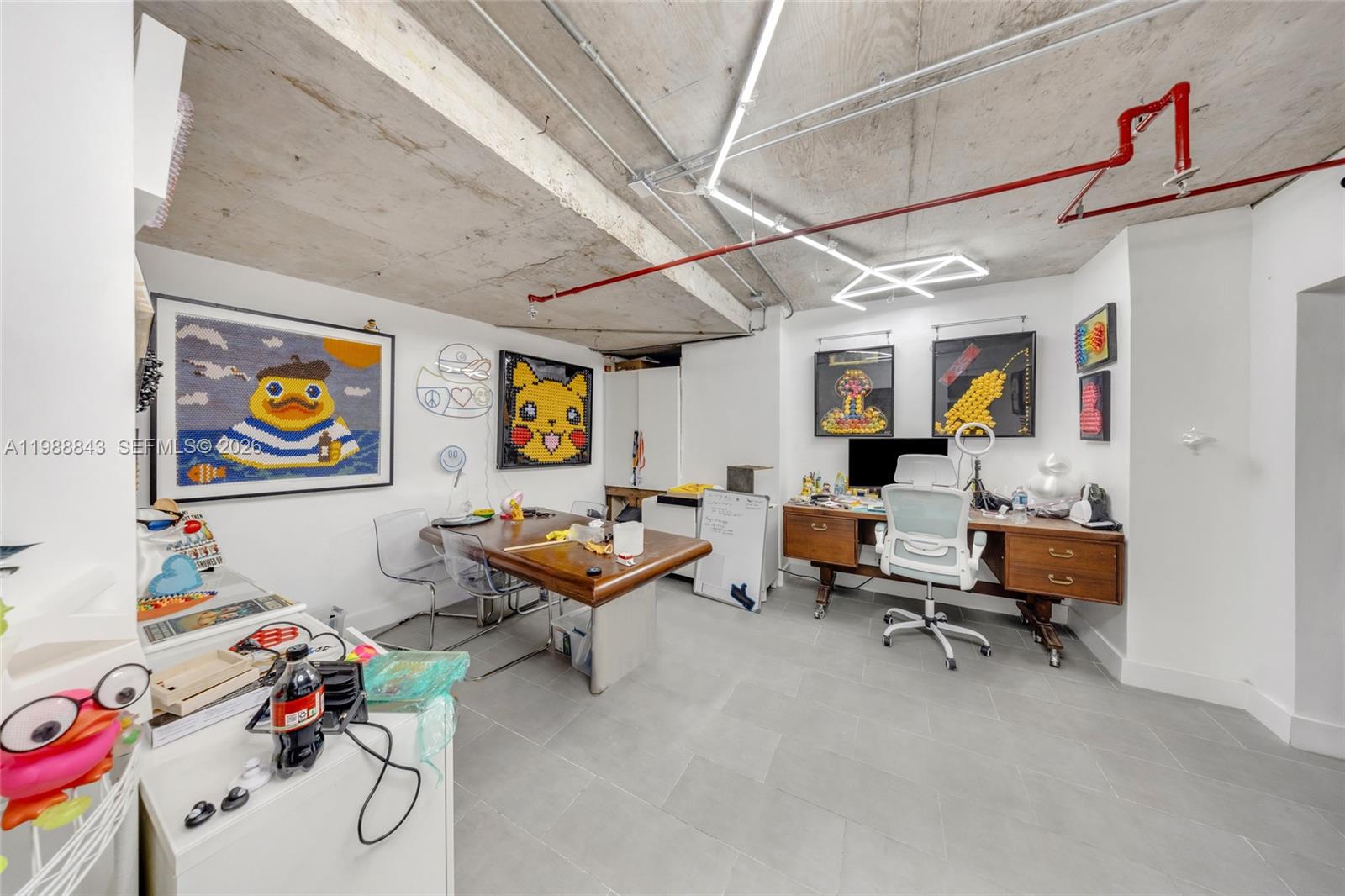 A home office features a wooden desk, a conference table, and colorful pop art decor — 5445 Collins Ave, Miami Beach FL 33140, MIAMI BEACH, FL